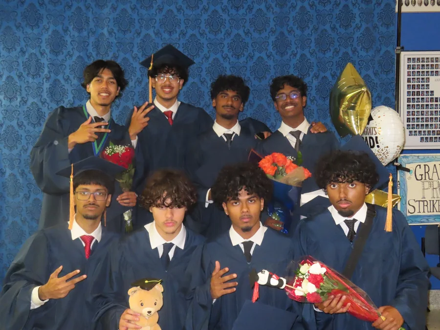 Ahnaf and friends in graduation gowns, holding flowers