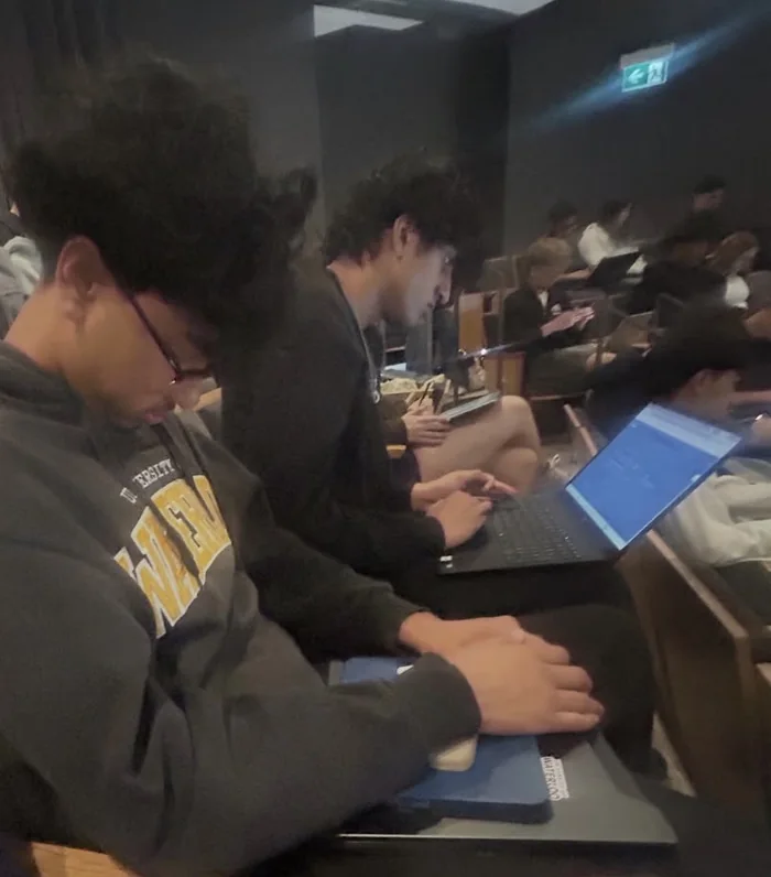 Ahnaf asleep over his tablet in a packed lecture hall