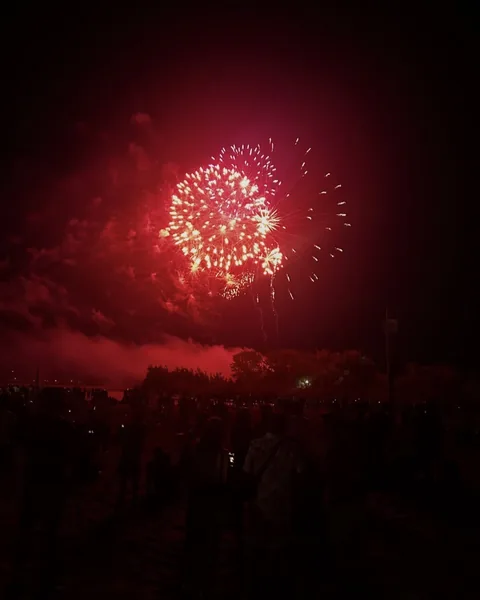 Red fireworks over a crowd by the lake
