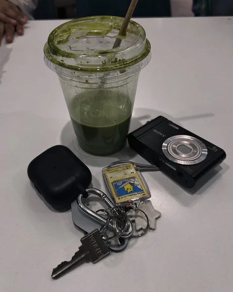 A matcha, a Sony camera and keys with a Pikachu keychain on a table